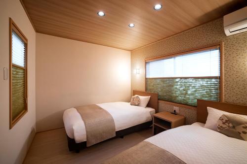2 letti in una piccola camera con finestra di Rinn Tsukinowa a Kyoto