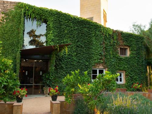 a building covered in green ivy with flowers and plants at Hotel Mas La Boella in La Canonja