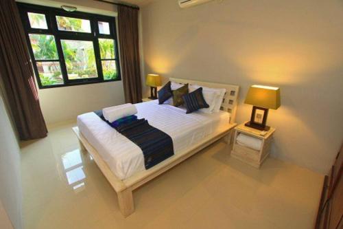 5 Bedroom Holiday Villa - Kuta Regency B8 في كوتا: غرفة نوم بسرير كبير مع نافذتين
