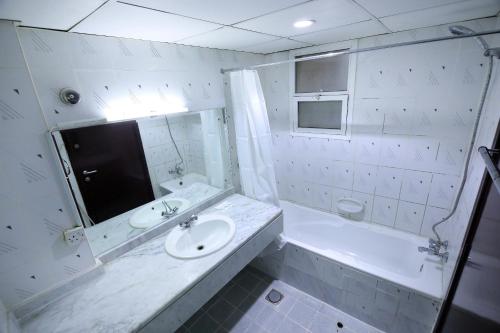 a white bathroom with a sink and a tub at OYO 912 Tanha Hotel in Dubai