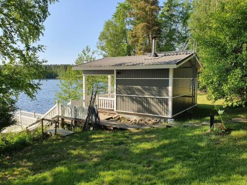 a small cabin on a dock next to a lake at Mökki ja rantasauna Saimaan rannalla in Taipalsaari