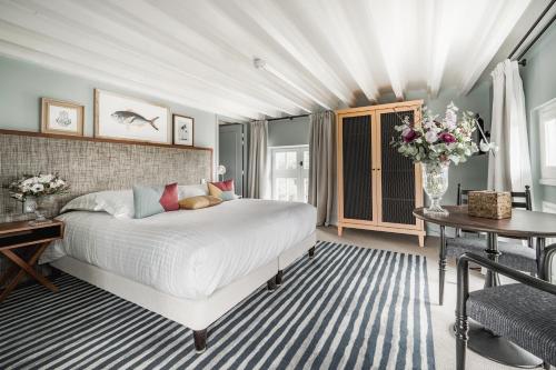um quarto com uma grande cama branca e uma mesa em Villa Arthus-Bertrand em Noirmoutier-en-l'lle