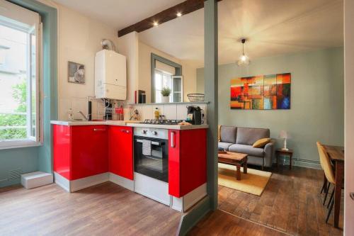 a kitchen with red cabinets and a living room at Le Beaumont in Rennes