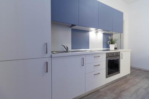 a white kitchen with a sink and a stove at Le Casette Di Osvaldo in Lecco