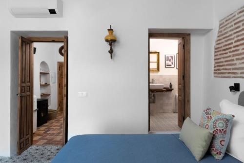 a bedroom with a blue bed and a bathroom at La AMARA Zaid - en el casco antiguo de Frigiliana in Frigiliana