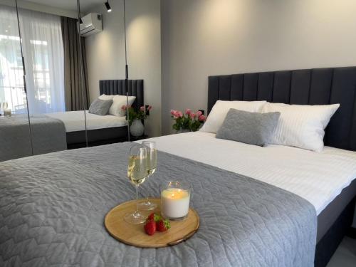 um quarto com uma cama com uma vela e copos de vinho em URBAN APARTMENTS PREMIUM DOWNTOWN Opolska 10 No 69 with GARAGE em Katowice