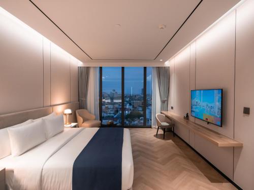 a hotel room with a large bed and a tv at Arbour Hotel and Residence in Pattaya Central