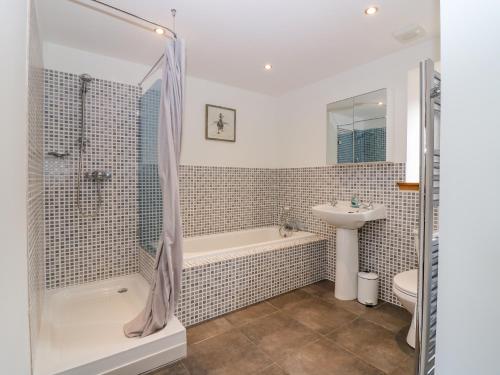 a bathroom with a shower and a tub and a sink at The Bothy in Peterhead