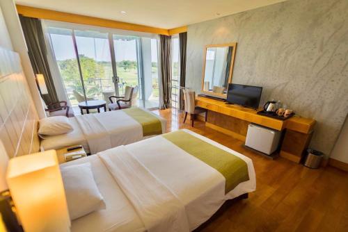 a hotel room with two beds and a television at Uniland Golf & Resort in Nakhon Pathom