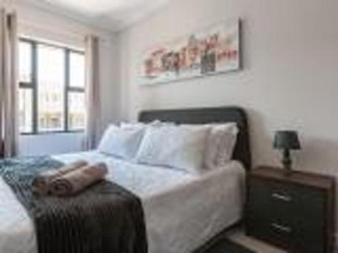 um quarto com uma cama com uma mesa de cabeceira e uma janela em The Rand Haven em Midrand