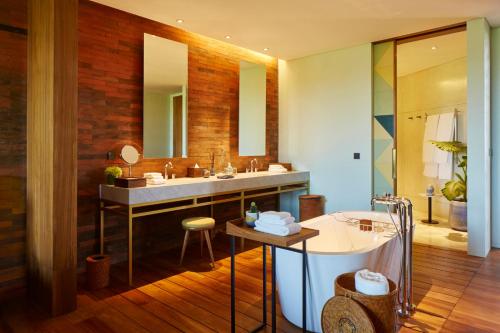 a bathroom with a sink and a tub and a mirror at Potato Head Suites & Studios in Seminyak