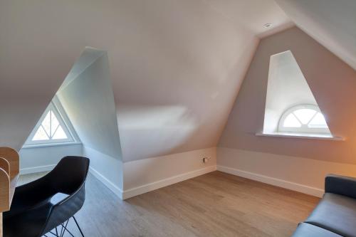 an attic room with two windows and a table and chairs at Rantum Dorf - Ferienappartments im Reetdachhaus 3 & 4 in Rantum