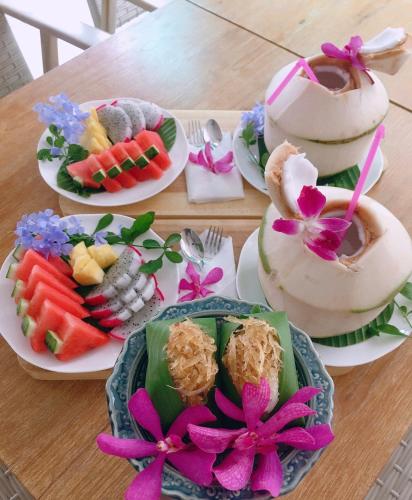 a table topped with plates of food and bowls of fruit at Wayside Guesthouse in Chiang Mai
