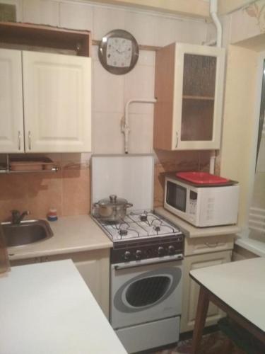 a small kitchen with a stove and a microwave at Уютная 1 комнатная квартира возле метро Дарница in Kyiv