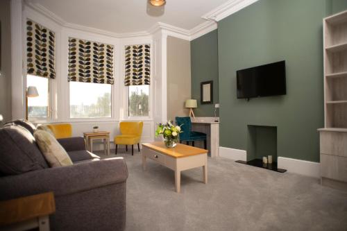 ein Wohnzimmer mit einem Sofa und einem TV in der Unterkunft Amadeus Apartments in Douglas