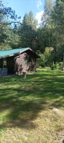 une petite maison dans une cour herbeuse avec un bâtiment dans l'établissement U Stefanów, à Królowy Most