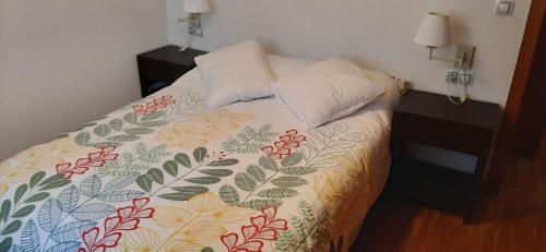 ein Schlafzimmer mit einem Bett mit Blumenbettdecke in der Unterkunft APARTAMENTO CENTRO DE SANXENXO con GARAJE in Sanxenxo