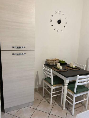 a table with two chairs and a clock on a wall at Appartamento Note di Jesi in Iesi