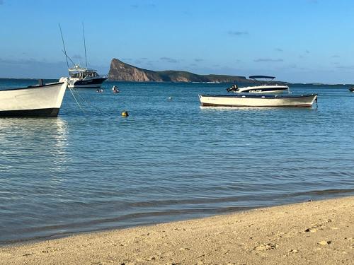 two boats in the water next to a beach at Coastal View Apartments in Grand Baie