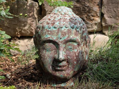 a statue of a head sitting in the grass at Lautertal Zinne in Hayingen