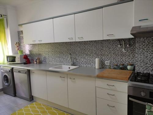 una cucina con mobili bianchi, un lavello e una lavastoviglie di A Casa da Nocas a Setúbal
