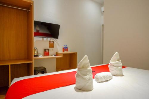 a bedroom with a red and white bed with towels at RedDoorz Plus @ Losari Makassar in Makassar