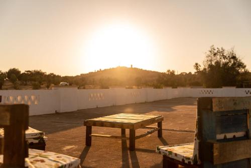 a picnic table in a parking lot with the sun setting at Herdade da Ordem in Cabeço de Vide