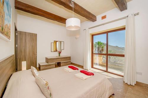 a bedroom with a bed and a large window at Tfiefa Holiday Home in Xagħra