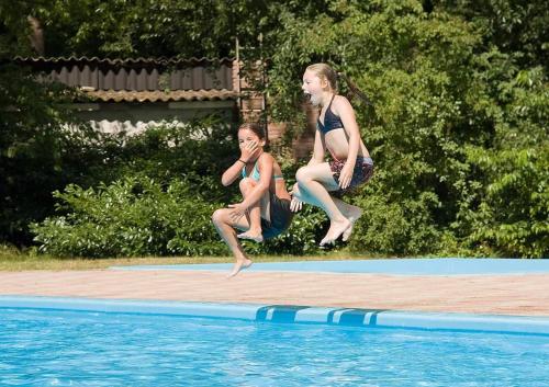 two girls jumping off of a swimming pool at Heerlijk bos chalet met ongekende rust en vrijheid in Nunspeet