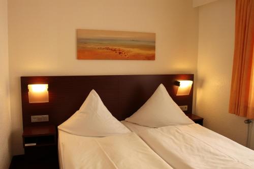 a bed in a hotel room with two pillows at Haus Sparkuhl Hotel Garni in Hannover