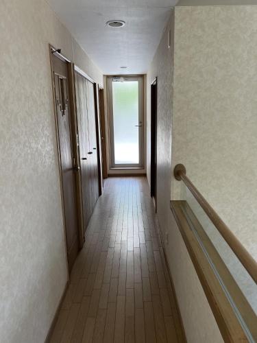 a hallway of a building with a door and stairs at Guest House SoL in Katsuura