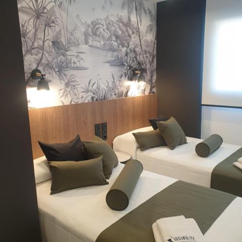 two beds in a room with a painting on the wall at Urbanlux Olimpia Familiar in Albacete