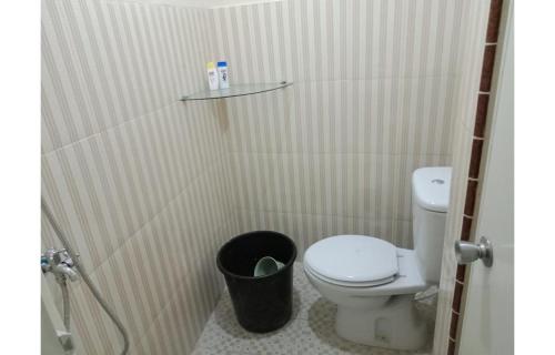a bathroom with a toilet and a trash can at Merpati Hostel Banyuwangi in Dadapan