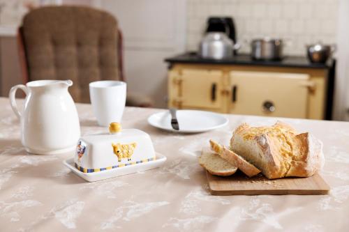 una mesa con un plato de pan y un hervidor de agua. en Suir Valley Cottage., 