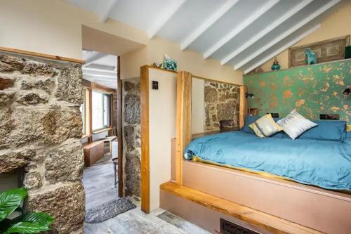 um quarto com uma cama azul e uma parede de pedra em The Olde Piggery, on the coast, Zennor, St Ives em Zennor
