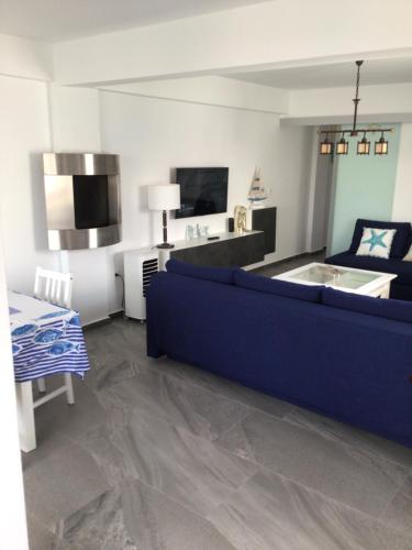 uma sala de estar com um sofá azul e uma televisão em Le Montemar em Alicante