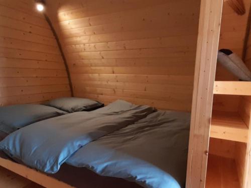 a bed in a wooden room with two bunk beds at Logement insolite Pod Lo Tchan in Fréland
