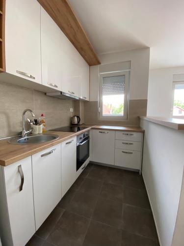 a kitchen with white cabinets and a sink at Cool Apartments with FREE PARKING in Čačak