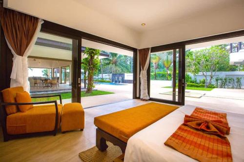 a bedroom with a bed and a chair and a large window at Baan Chom Tawan Villa in Lipa Noi