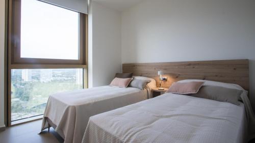2 camas en una habitación con ventana grande en INTEMPO Sky Apartments 213, en Benidorm