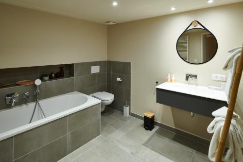 La salle de bains est pourvue d'une baignoire, de toilettes et d'un lavabo. dans l'établissement Pêche de Vigne & Spa, à Rodern