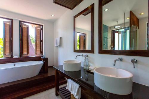 y baño con 2 lavabos, bañera y espejo. en Baan Chom Tawan Villa en Lipa Noi