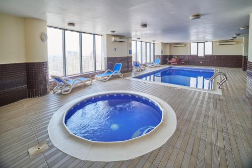 a large swimming pool with a large tub in a hotel room at Vita Tower in Manama