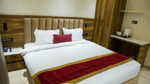 a bedroom with a large white bed with red pillows at Royal 9 hotel & Banquet in Meerut
