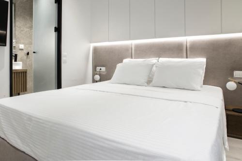 un grande letto bianco con due cuscini sopra di Ultra Chic Modern 4 Bedrooms Apartment in Athens ad Atene