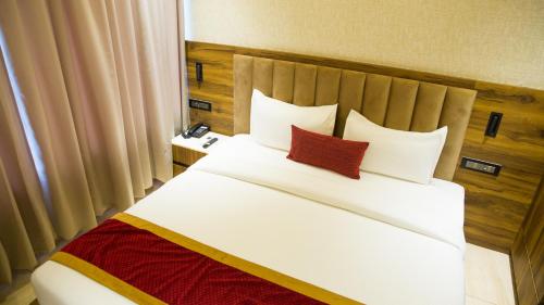 a bedroom with a large white bed with red pillows at Royal 9 hotel & Banquet in Meerut