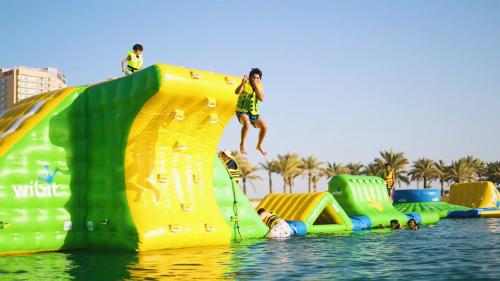 a group of people jumping off a water slide in the water at The Art Hotel & Resort in Manama