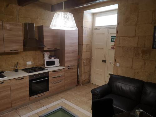 a small kitchen with a couch and a microwave at Two gate town house in Senglea