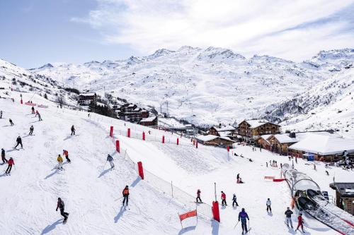 a group of people skiing down a snow covered slope at Hôtel Les Menuires Les Bruyères in Les Menuires