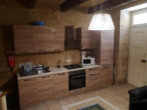 a kitchen with wooden cabinets and a sink and a microwave at Two gate town house in Senglea